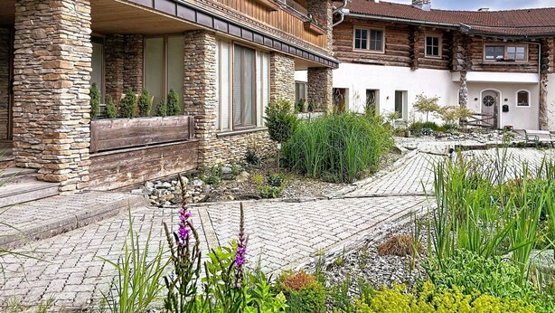Eine zweistöckige Holzhütte mit Steinmauern und einem Balkon mit roten Blumen.