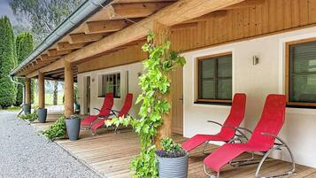 A covered outdoor seating area with red chairs and potted plants.