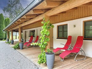 A covered outdoor seating area with red chairs and potted plants.