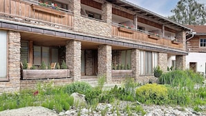 A multi-story log cabin with stone pillars, balconies with wooden railings, and a covered porch area.