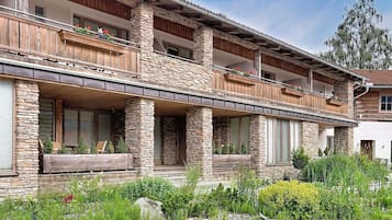 A multi-story log cabin with stone pillars, balconies with wooden railings, and a covered porch area.