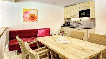 A compact living space with a dining area, kitchenette, and a red sofa.