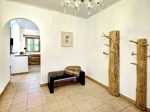 Ein Flur mit einer Bank, einem Holz-Kleiderständer und einem gerahmten Bild an der Wand.