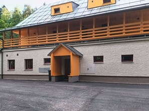 Ein Gebäude mit einem geneigten Dach, Holzbalkonen und einem kleinen, giebelverzierten Eingang.