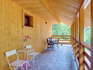 Interior de madera con un patio cubierto, suelo de piedra y vistas a zonas verdes.