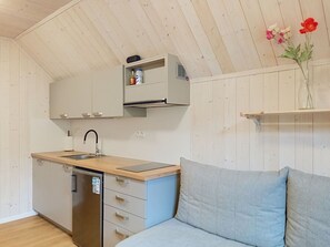 Eine kompakte Küche mit integriertem Geschirrspüler, einer Holz Arbeitsplatte und einem einzelnen Spülbecken.