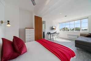 A modern bedroom with a large bed, a desk, and a view of the city. - Charming South Kensington Stay (London)
