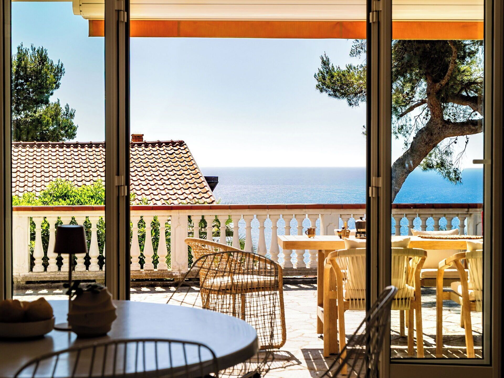 Eine Terrasse mit Meerblick, Sitzgelegenheiten im Freien und einem Ziegeldach.