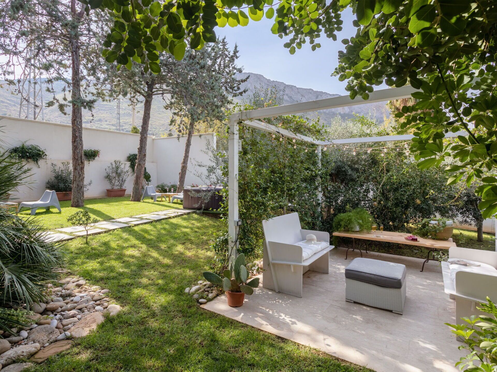 A patio with outdoor furniture, a pergola, and a garden area with trees and plants.