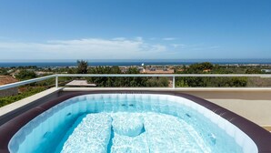Ein Außen-Whirlpool mit freiem Blick auf das Meer und die umliegende Landschaft.