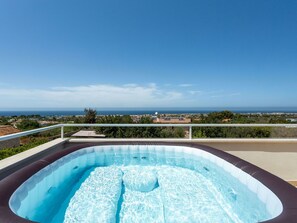 En utomhusbubbelpool med fri utsikt över havet och det omgivande landskapet.
