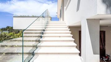 Una moderna scala con ringhiere in vetro che conduce a un edificio bianco.