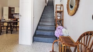 Escada que leva a um hall com área de jantar, cozinha e um espelho fixado na parede.