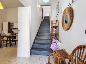 Eine Treppe führt zu einer Zwischenebene mit einem Essbereich, einer Küche und einem wandmontierten Spiegel.
