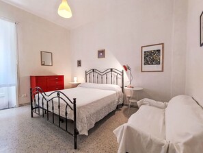 Ein Schlafzimmer mit einem Bett, einem Nachttisch, einer Lampe und einer roten Kommode.