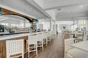 A spacious bar area with a long counter, white bar stools, and a variety of bottles and glasses. - The Beach Club 104C by Liquid Life (Gulf Shores)