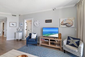 Un salon avec une télévision, une horloge et des œuvres d’art accrochées au mur.