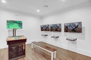 A gallery with paintings, a television, and a bench. - The Beach Club 104C by Liquid Life (Gulf Shores)