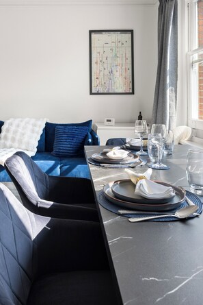 A neatly arranged dining area with a table set for four, a bed with blue bedding, and a wall-mounted timeline of world history. - Great Titchfield Street 1Bed 1Bath in the heart of London. Newly refurnished (London)