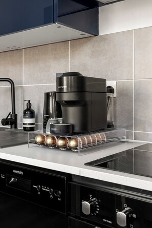 A kitchen with a black coffee machine, a kettle, and a bottle of hand soap. - Great Titchfield Street 1Bed 1Bath in the heart of London. Newly refurnished (London)