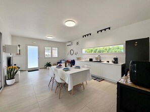 Eine moderne Küche mit Essbereich, weißen Schränken und einem großen Fenster.