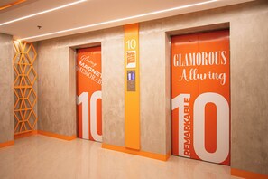 Un ascensor moderno con señalización llamativa, que incluye las palabras 'Glamorous Alluring' y 'Remarkable' en las puertas.