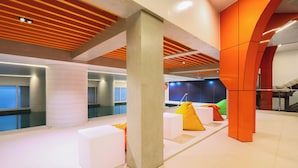 Un espacio interior moderno con piscina, zonas de estar y una escalera.