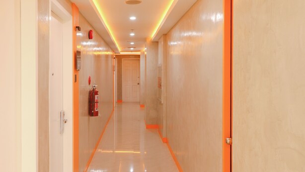 Un pasillo con extintor, una puerta y detector de incendios en la pared.