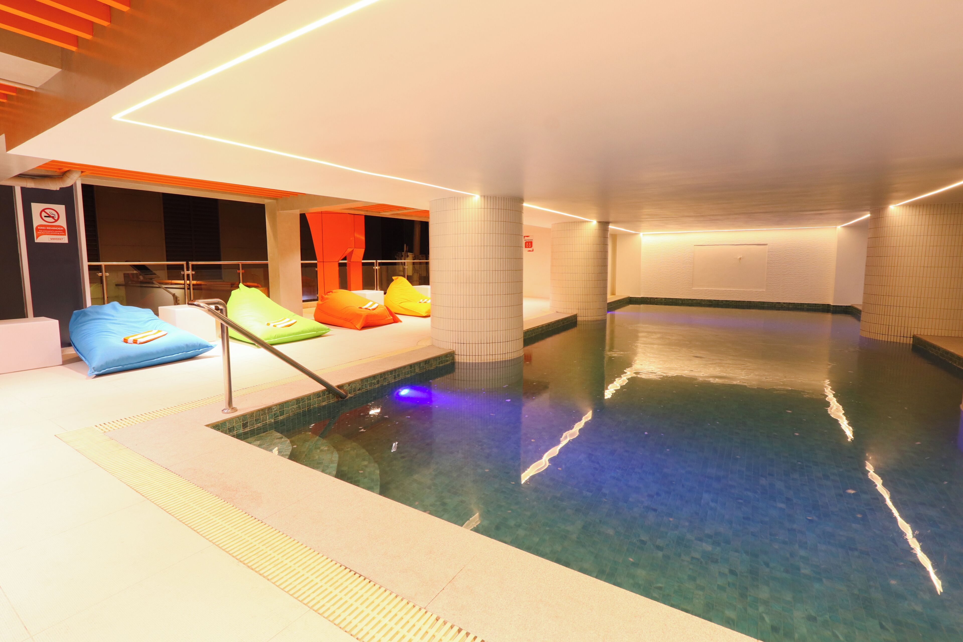 An indoor swimming pool with a seating area and a no smoking sign.