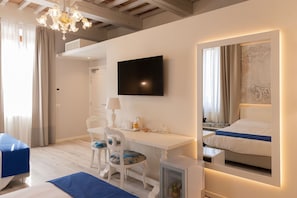 A hotel room with a bed, a desk, a chair, a television, and a mirror.