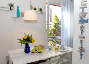 A breakfast table with fruits, a vase of sunflowers, and a lamp.