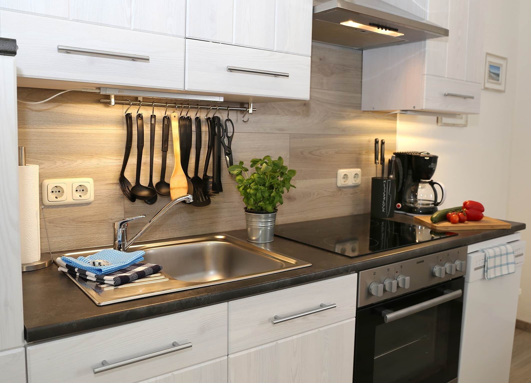 A modern kitchen with a stainless steel sink, a built-in oven, and a coffee maker.