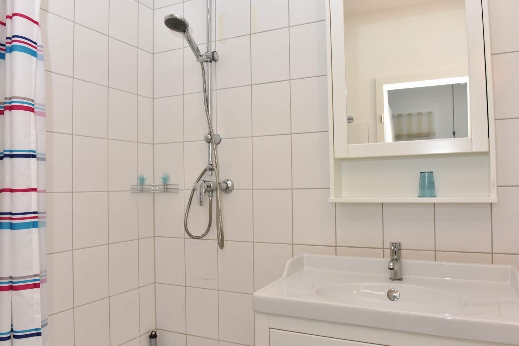 Ein Badezimmer mit Dusche, Waschbecken, Spiegel und einem gestreiften Duschvorhang.