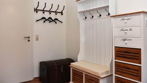 Une pièce comprenant un porte-manteau, une commode et un petit banc.