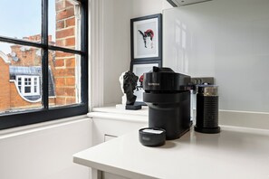 A kitchen with a coffee machine, a kettle, and a small appliance on the counter. - Marylebone’s Nest 1Bed (London)
