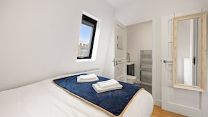 A bedroom with a bed, a window, a door, and a view of the city. - Marylebone’s Nest 1Bed (London)