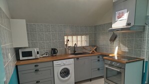 A compact kitchen with a washing machine, microwave, and oven. - L'Erable du Perche (Tourouvre au Perche)