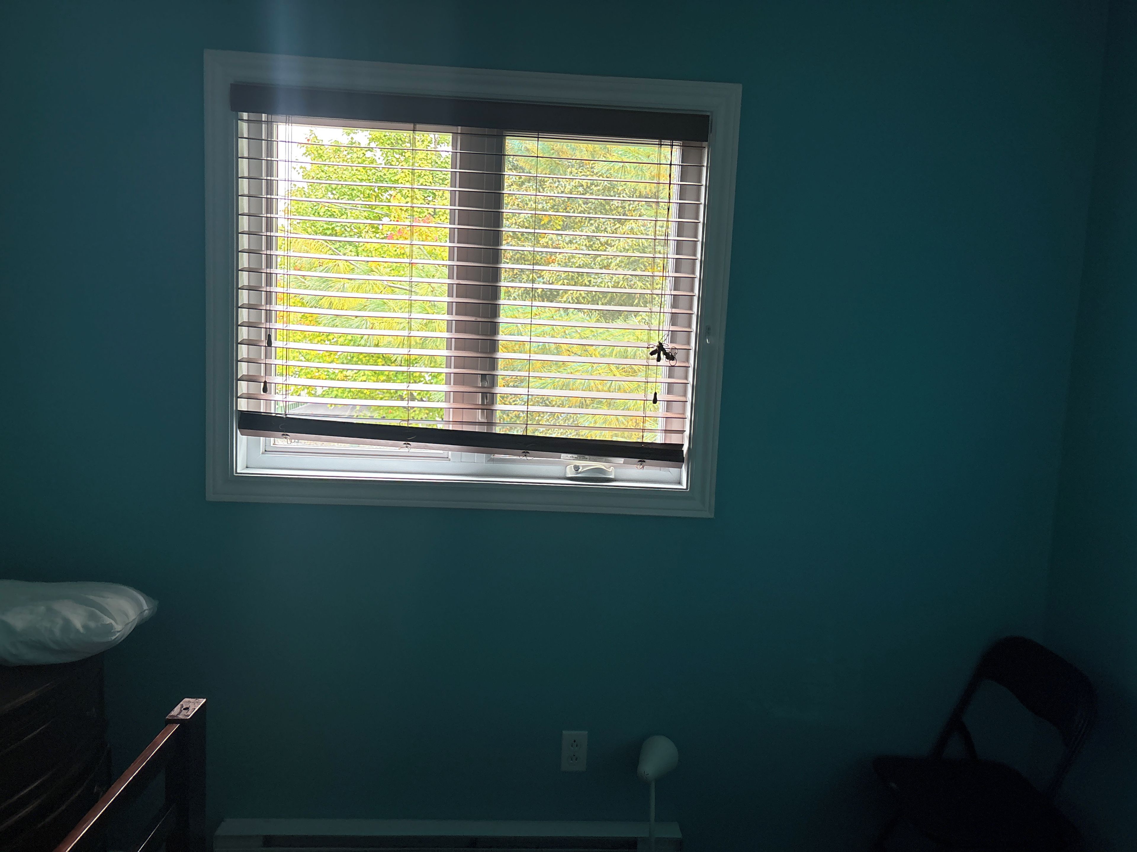 A room with a window, a bed, a nightstand, and a chair.