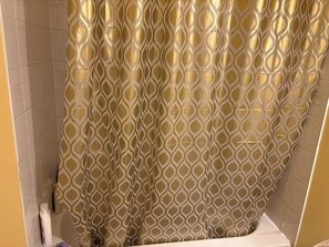 A bathroom with a patterned shower curtain, tiled walls, and a white bathtub. - Bienvenu Chez toi! (Gatineau)