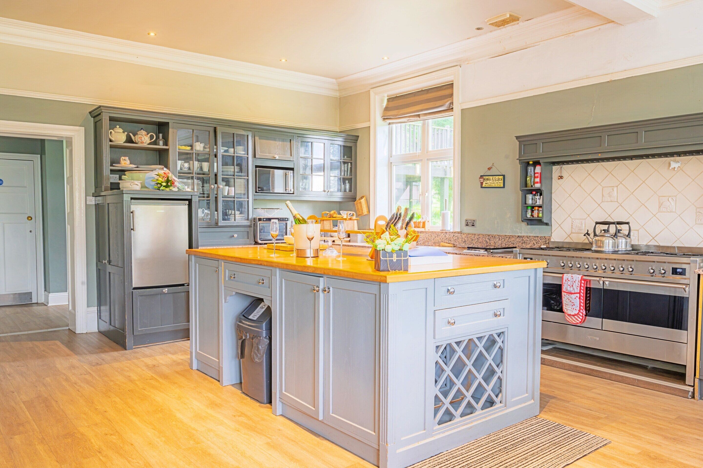 A spacious kitchen with a central island, built-in appliances, and a view to the outside.