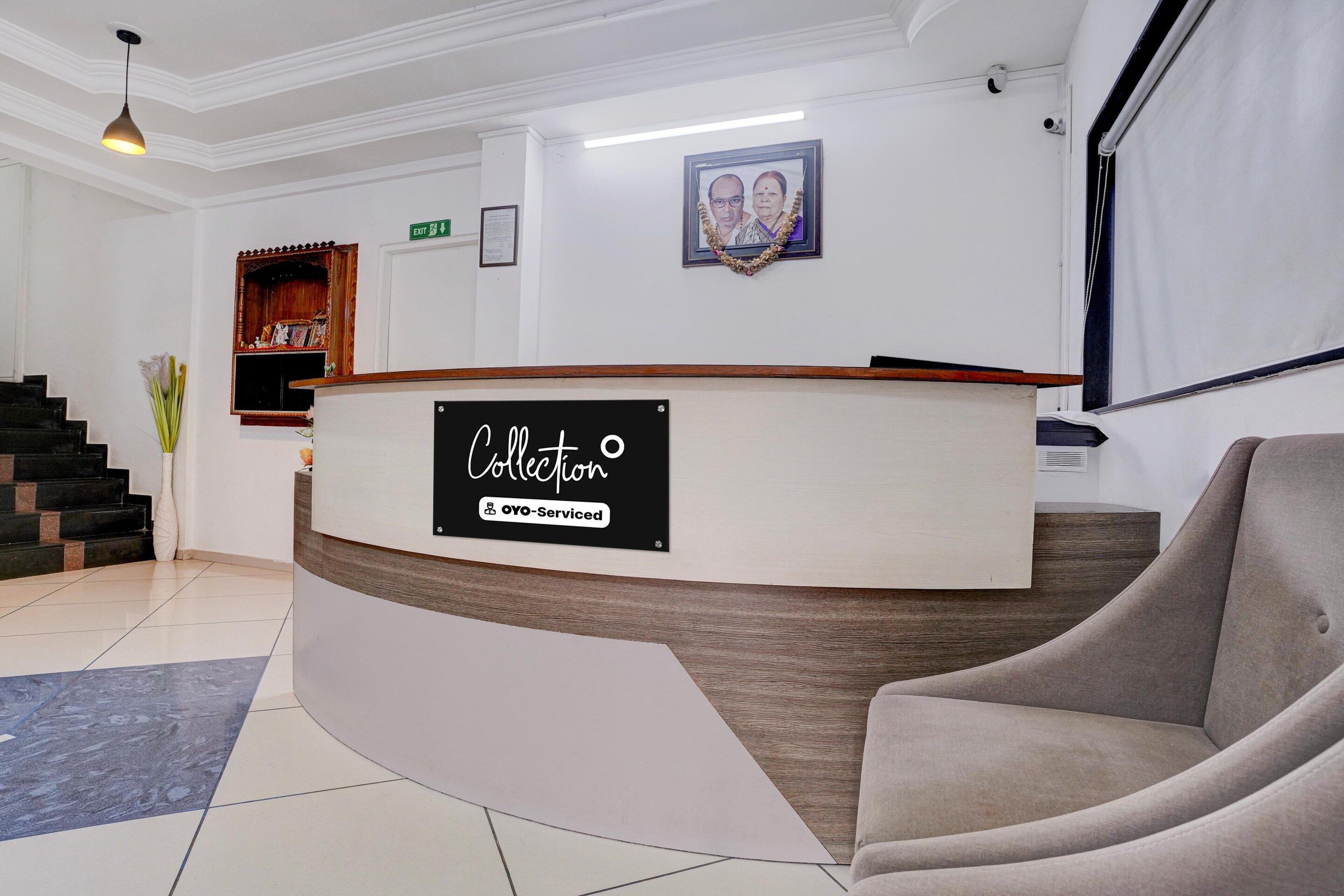 A reception area with a curved reception desk, a framed photograph on the wall, and a staircase with a vase of flowers.