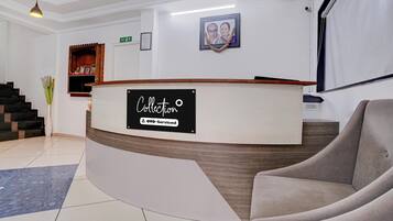 A reception area with a curved reception desk, a framed photograph on the wall, and a staircase with a vase of flowers.