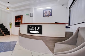 A reception area with a curved reception desk, a framed photograph on the wall, and a staircase with a vase of flowers.