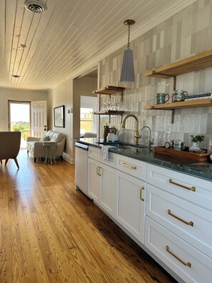 A kitchen with white cabinetry, a wooden countertop, and a hanging light fixture. - NEW! Restored Oceanfront Cottage •  Vintage Charm • Walk to Dining (Topsail Beach)
