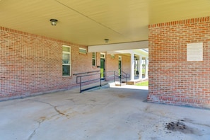 A covered walkway with brick walls, metal railings, and a sign with parking instructions.