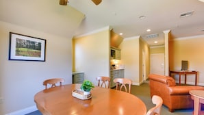 A dining area with a wooden table, chairs, and a plant centerpiece. - Pool Access + Golf View: 5BR Springfield Home (Springfield)