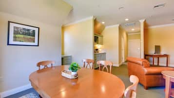 A dining area with a wooden table, chairs, and a plant centerpiece.