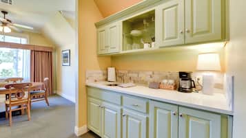 A kitchen with light green cabinets, a white countertop, and a ceiling fan.