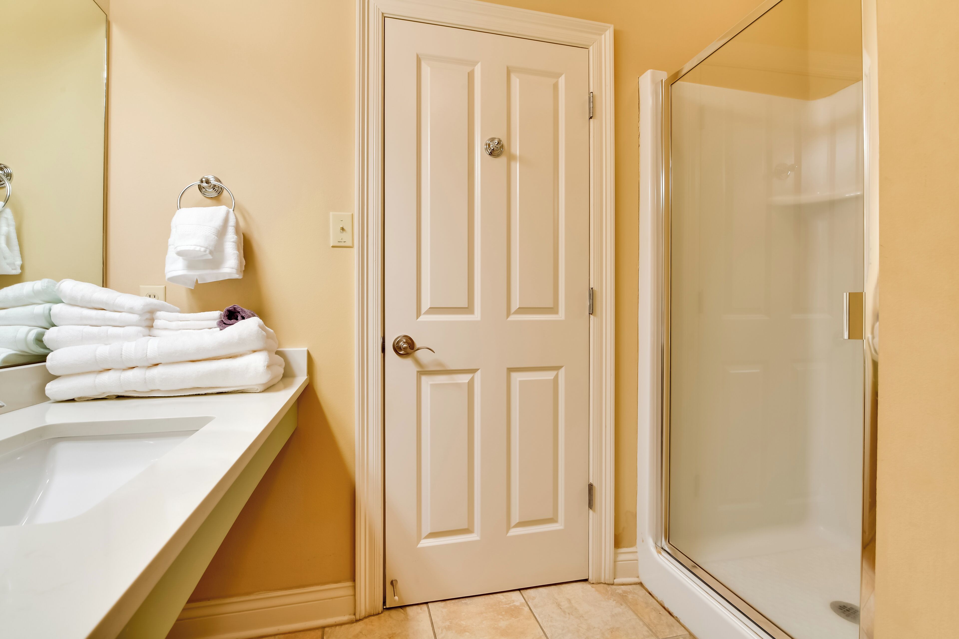 A bathroom with a white door, a sink, and a glass shower enclosure.