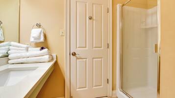 A bathroom with a white door, a sink, and a glass shower enclosure.